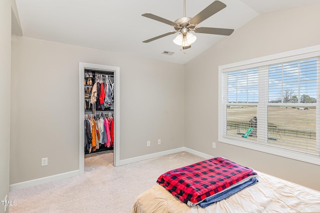 carpeted bedroom with a walk in closet, lofted ceiling, a closet, visible vents, and baseboards