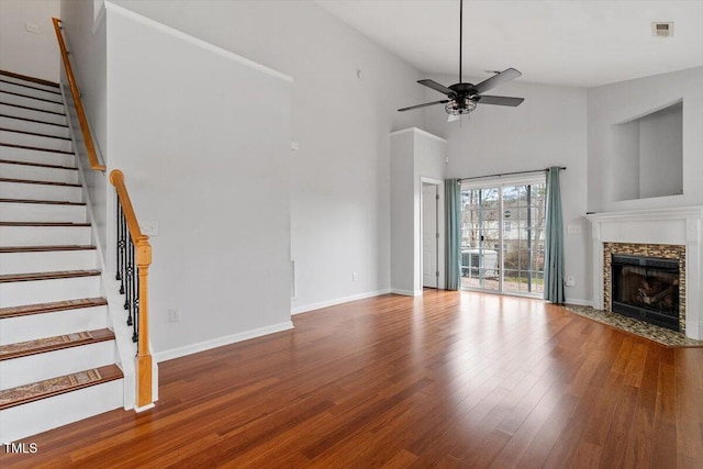 unfurnished living room featuring visible vents, wood finished floors, stairway, a fireplace, and baseboards