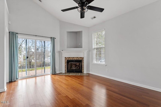 unfurnished living room with visible vents, baseboards, lofted ceiling, a fireplace, and wood finished floors