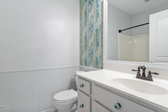 full bathroom with a shower, a wainscoted wall, toilet, and vanity