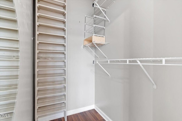 walk in closet with dark wood-style flooring