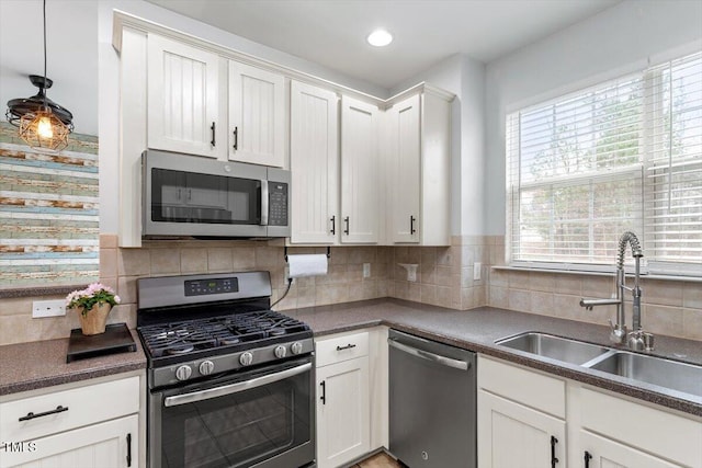 kitchen featuring tasteful backsplash, stainless steel appliances, dark countertops, and a sink