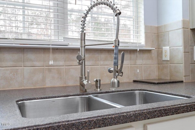 details featuring a sink, decorative backsplash, and dark stone countertops