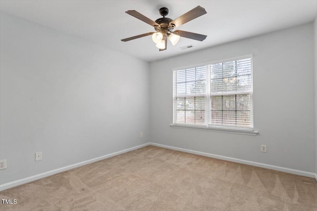 empty room featuring ceiling fan, light colored carpet, visible vents, and baseboards