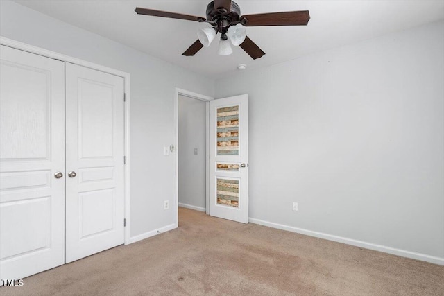 unfurnished bedroom featuring a closet, baseboards, light colored carpet, and a ceiling fan