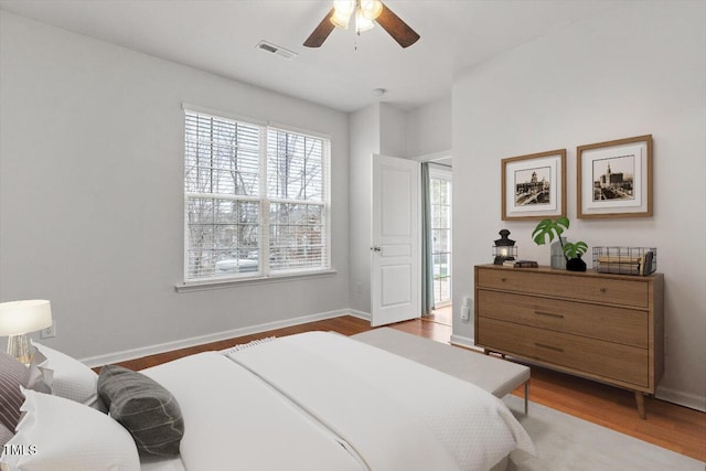 bedroom featuring visible vents, baseboards, wood finished floors, and a ceiling fan