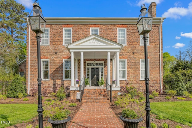 view of front facade featuring brick siding, a porch, and a chimney