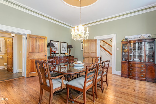 dining space with wood finished floors, baseboards, ornamental molding, and stairs