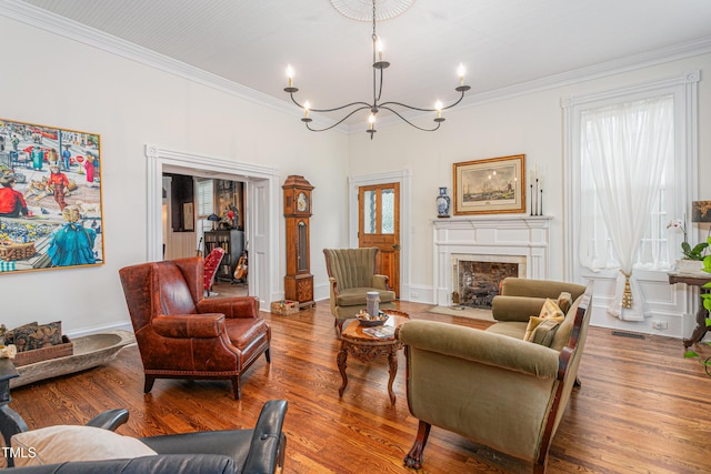 living room featuring a fireplace with flush hearth, crown molding, wood finished floors, and an inviting chandelier