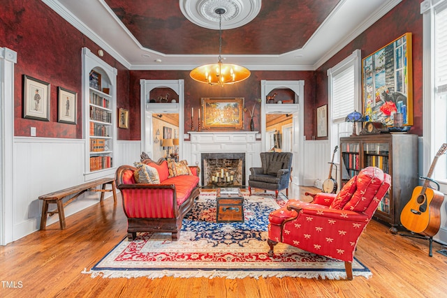 living area featuring a raised ceiling, an inviting chandelier, wood finished floors, and a fireplace