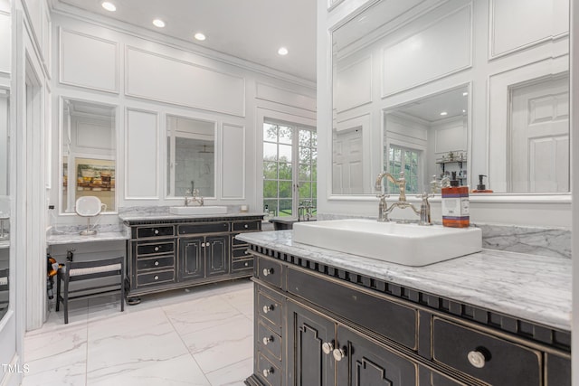 bathroom with a decorative wall, marble finish floor, a sink, and crown molding