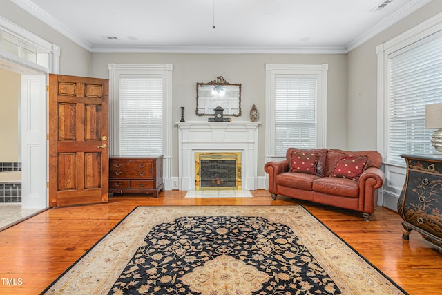 living area with plenty of natural light, hardwood / wood-style floors, and crown molding
