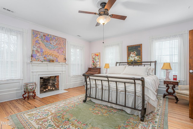 bedroom with crown molding, hardwood / wood-style flooring, and a fireplace with flush hearth