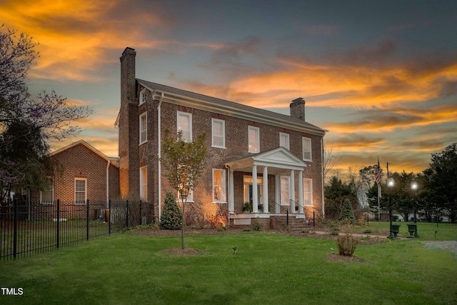 back of property featuring a yard, fence, brick siding, and a chimney