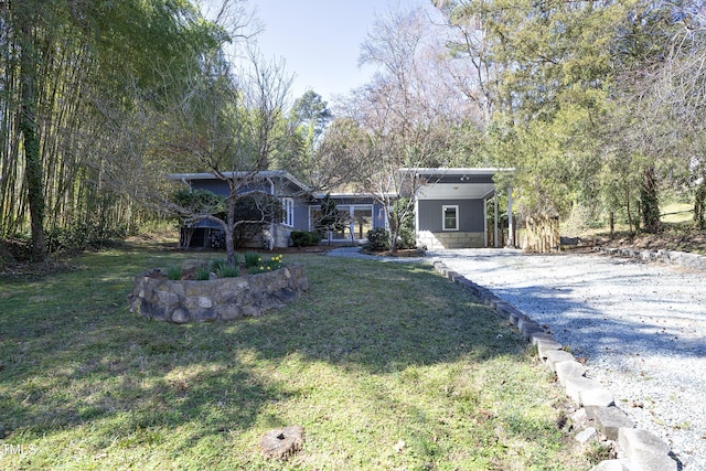 view of front facade featuring a carport, a front yard, and driveway