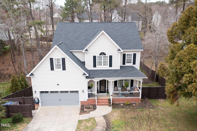 traditional home with a garage, fence, a porch, and a shingled roof