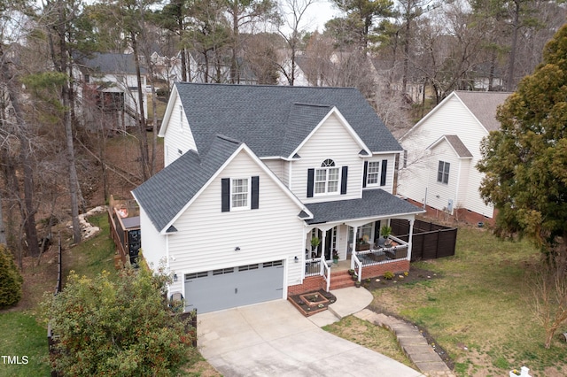 traditional-style house featuring a front lawn, covered porch, concrete driveway, an attached garage, and a shingled roof