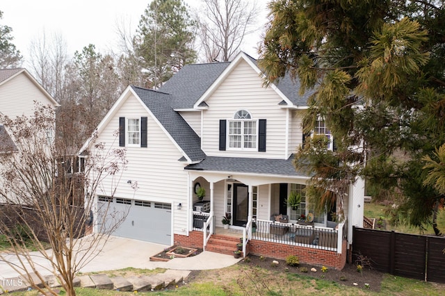 traditional-style home featuring a porch, fence, driveway, and a shingled roof