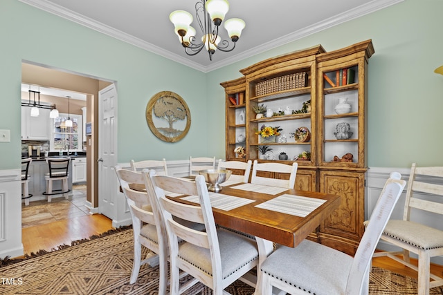 dining room with a notable chandelier, light wood-style floors, and ornamental molding