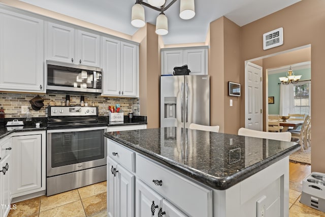 kitchen with a chandelier, a kitchen island, backsplash, and stainless steel appliances