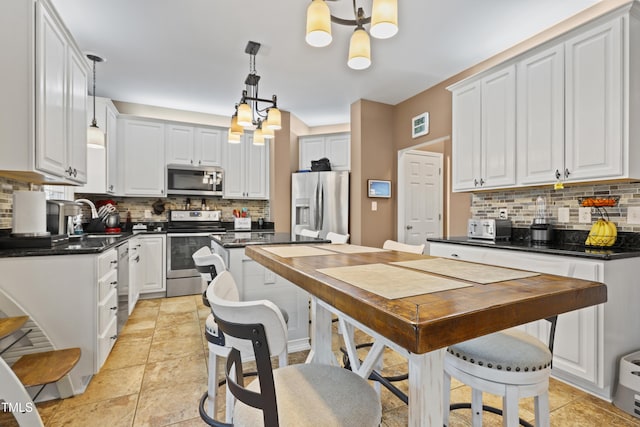 kitchen featuring a sink, dark countertops, appliances with stainless steel finishes, and white cabinets