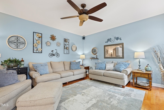 living room featuring light wood-type flooring, baseboards, and a ceiling fan