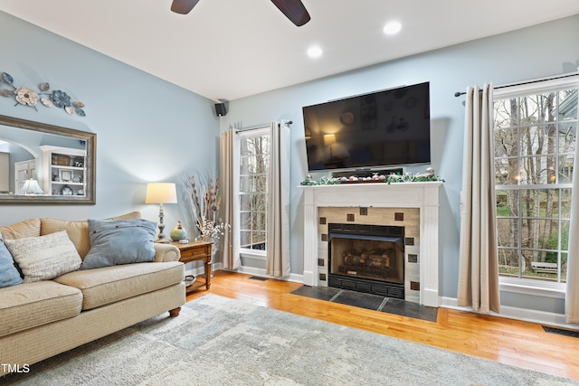 living room with a fireplace, wood finished floors, visible vents, and a healthy amount of sunlight