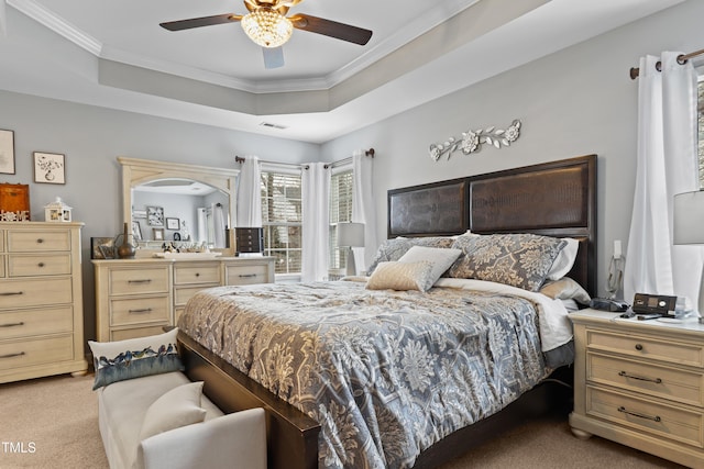 bedroom with visible vents, light colored carpet, crown molding, and a tray ceiling