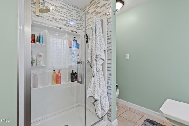 bathroom with tile patterned floors, a shower stall, toilet, and baseboards