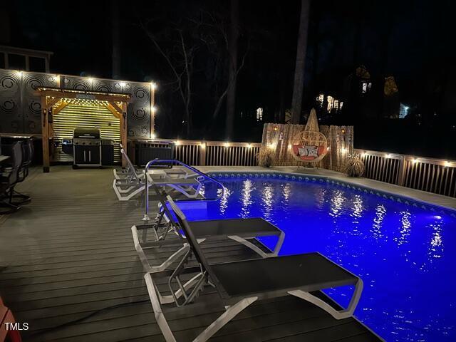 pool at twilight featuring a fenced in pool and a wooden deck