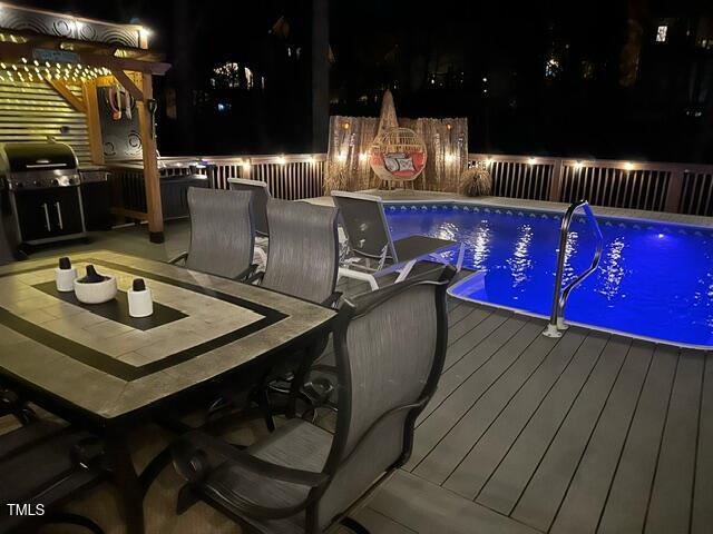 pool featuring outdoor dining area, area for grilling, a deck, and fence