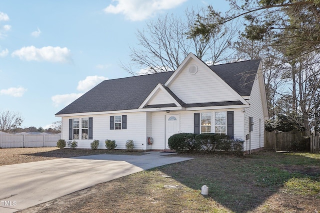 traditional-style home featuring roof with shingles and fence