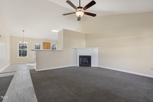 unfurnished living room featuring baseboards, dark carpet, a fireplace, high vaulted ceiling, and ceiling fan with notable chandelier