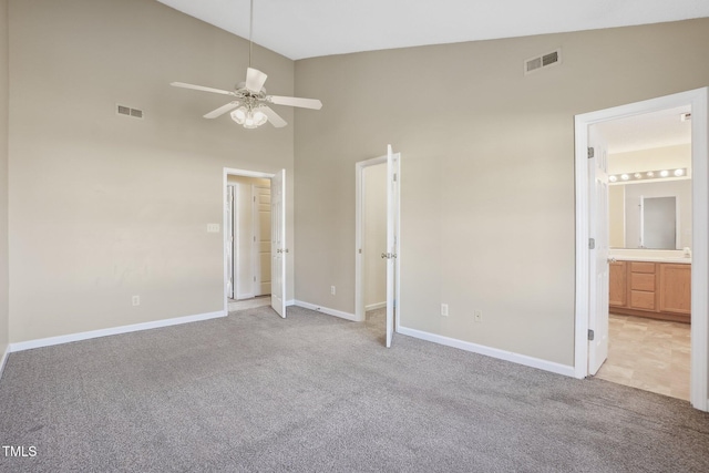 unfurnished bedroom with high vaulted ceiling, light carpet, visible vents, and baseboards