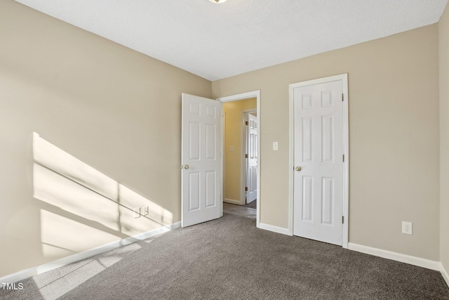 unfurnished bedroom with dark colored carpet and baseboards