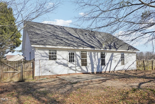 back of property featuring a patio, a shingled roof, fence, and a gate