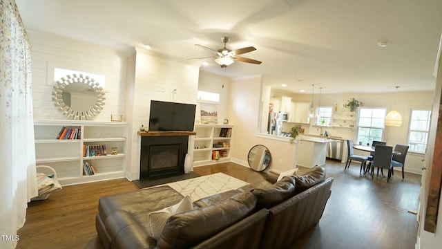 living room featuring dark wood-type flooring, a fireplace with flush hearth, a ceiling fan, and baseboards