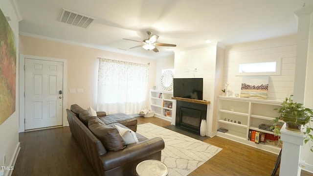 living area featuring a fireplace, visible vents, a ceiling fan, ornamental molding, and wood finished floors