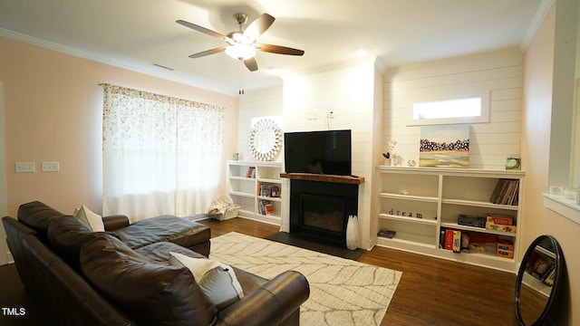 living area featuring crown molding, visible vents, a fireplace with flush hearth, ceiling fan, and wood finished floors