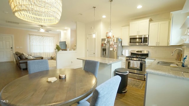 kitchen featuring stainless steel appliances, dark wood-type flooring, a kitchen island, a sink, and decorative backsplash