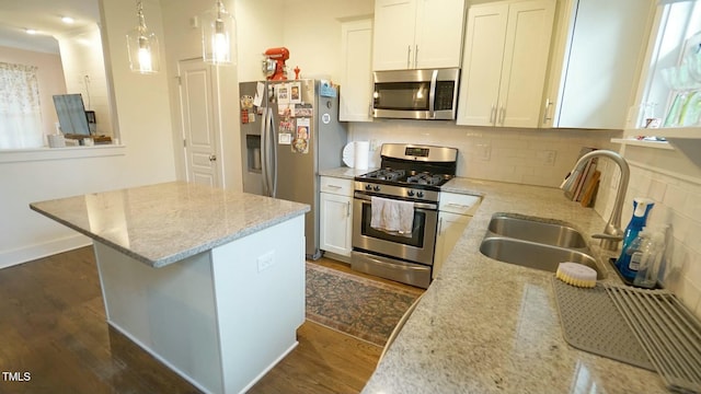 kitchen featuring tasteful backsplash, dark wood-style floors, a kitchen island, stainless steel appliances, and a sink