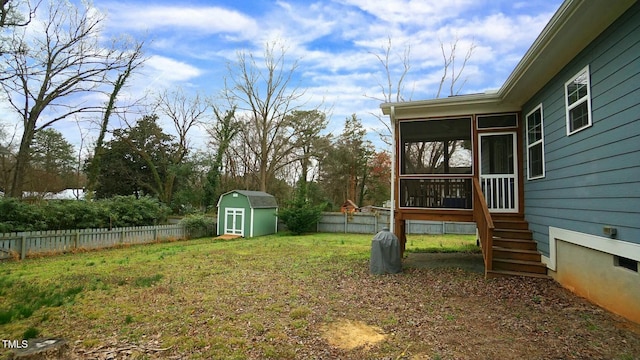 view of yard featuring a shed, an outdoor structure, a fenced backyard, and a sunroom