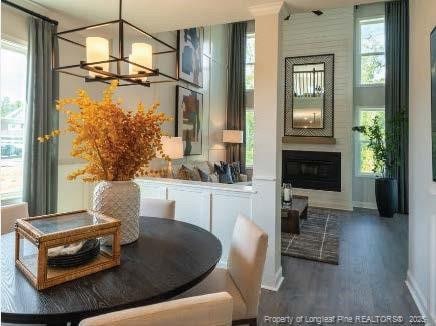 dining room with a large fireplace, wood finished floors, and a chandelier