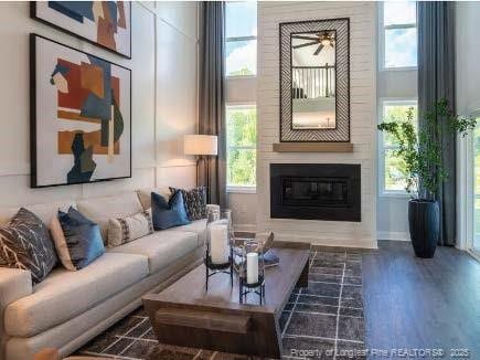 living area featuring a large fireplace, plenty of natural light, a towering ceiling, and wood finished floors