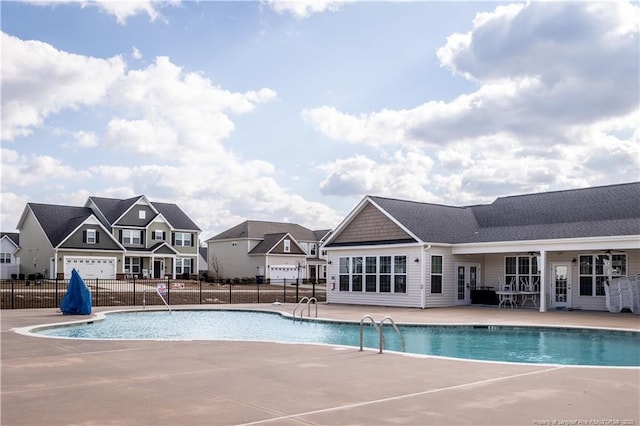 community pool with french doors, a patio area, fence, and a residential view