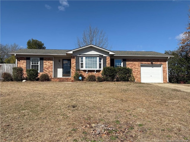 ranch-style home featuring a garage, brick siding, a front lawn, and fence