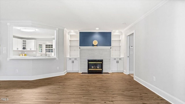 unfurnished living room with a glass covered fireplace, baseboards, and wood finished floors