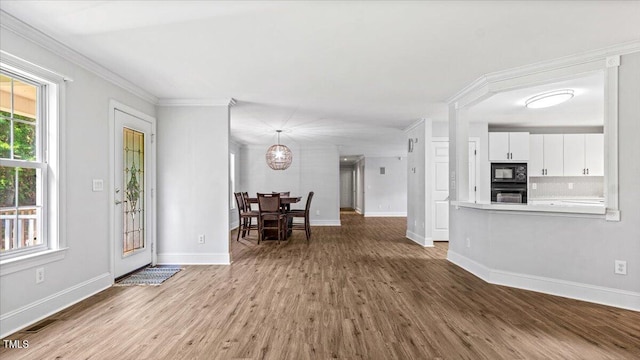 foyer entrance featuring baseboards, wood finished floors, visible vents, and crown molding