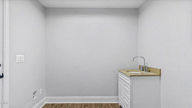 clothes washing area with baseboards, dark wood finished floors, and a sink