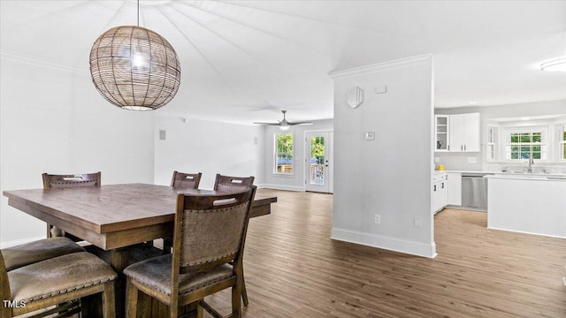 dining space featuring ornamental molding, light wood-style flooring, and baseboards